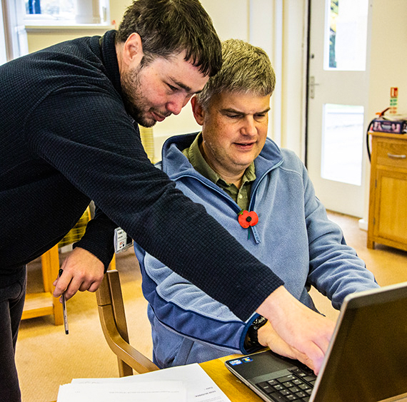 GRCC staff member helps a drop-in visitor with their laptop