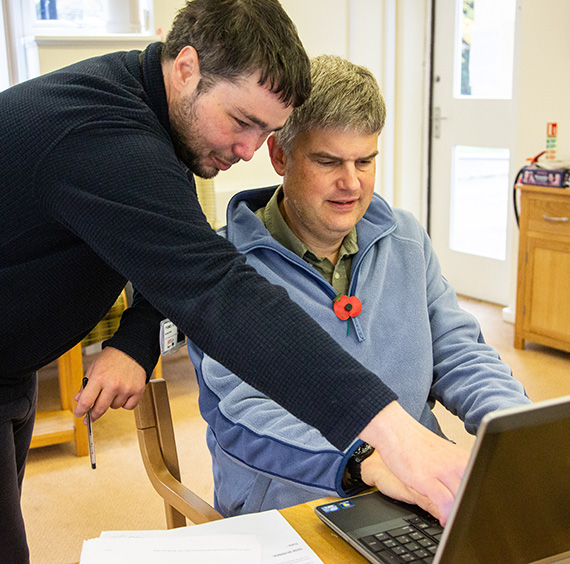 GRCC staff member helps a drop-in visitor with their laptop